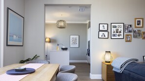 A modern living room with a wooden dining table, grey chairs, a blue sofa, and a small side table with a lamp. - JOIVY Splendid 2-Br Apartment In New Town (Edinburgh)