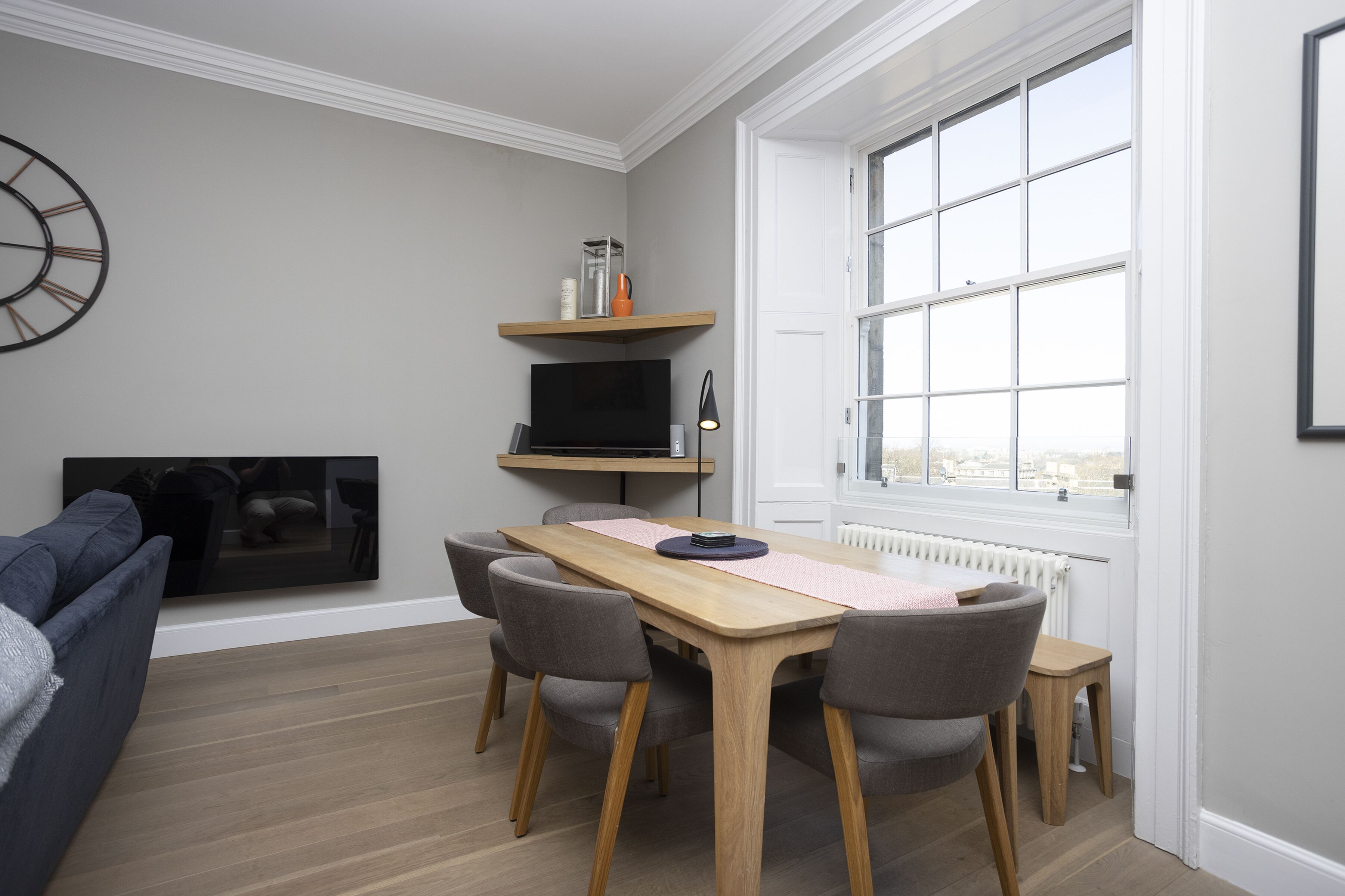Un salon moderne avec une table à manger, des chaises grises, un téléviseur et une cheminée.