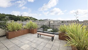 A rooftop terrace with a bench, potted plants, and a city view. - JOIVY Executive 2-Bed Apt With Stunning Roof Terraces (Edinburgh)