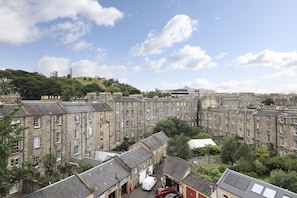 A cluster of historic stone buildings with uniform windows and a central green hill.