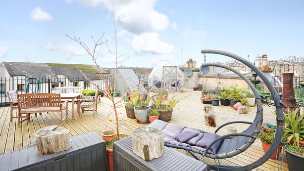 A rooftop terrace with wooden furniture, potted plants, and a hanging chair. - JOIVY Modern 1-Br Apt W/ Communal Terrace In Trendy Stockbridge (Edinburgh)