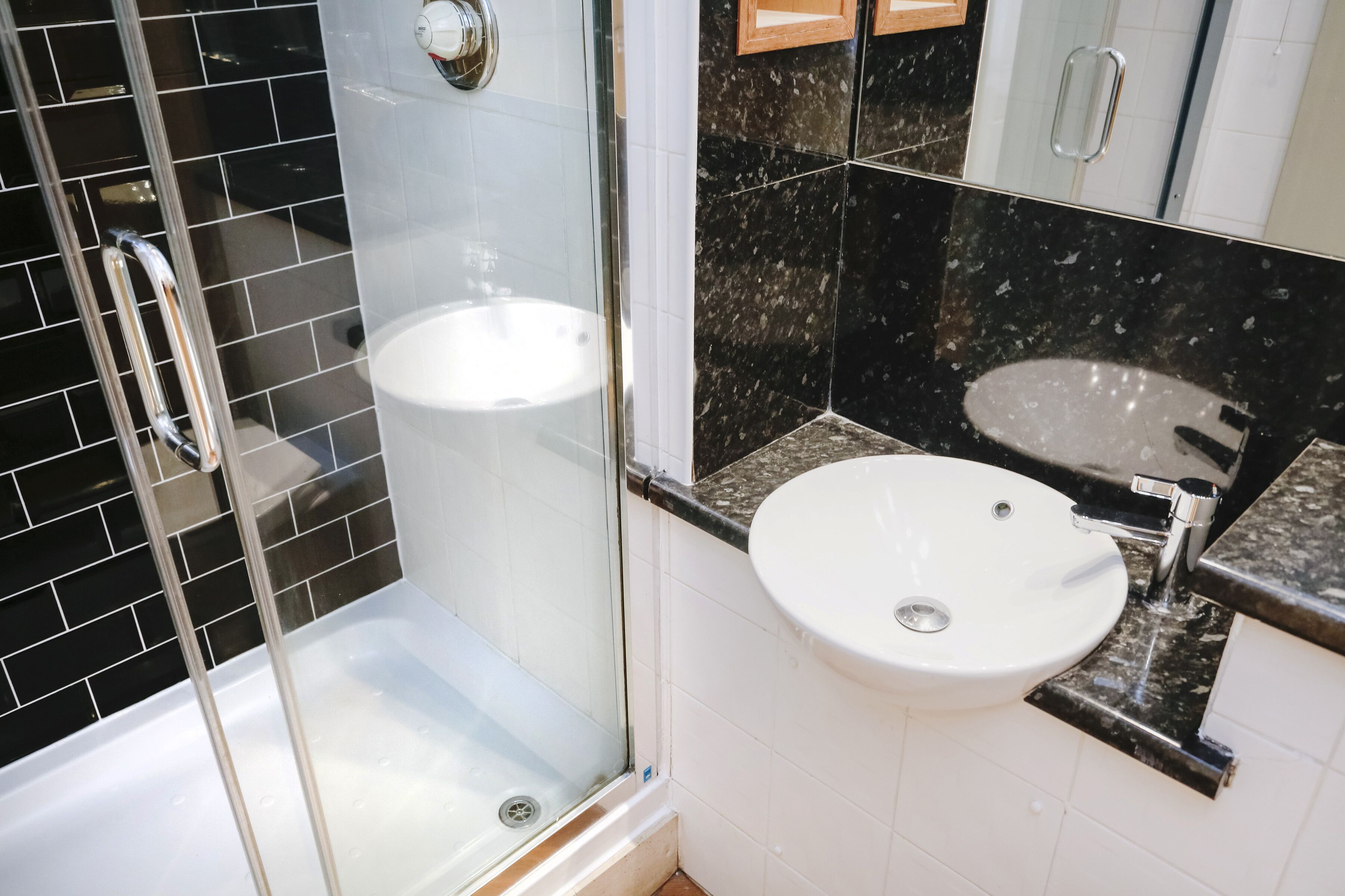 A bathroom with a glass-enclosed shower, a white sink, and a mirror above the sink.