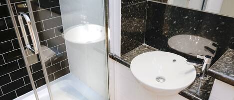 A bathroom with a glass-enclosed shower, a white sink, and a mirror above the sink.