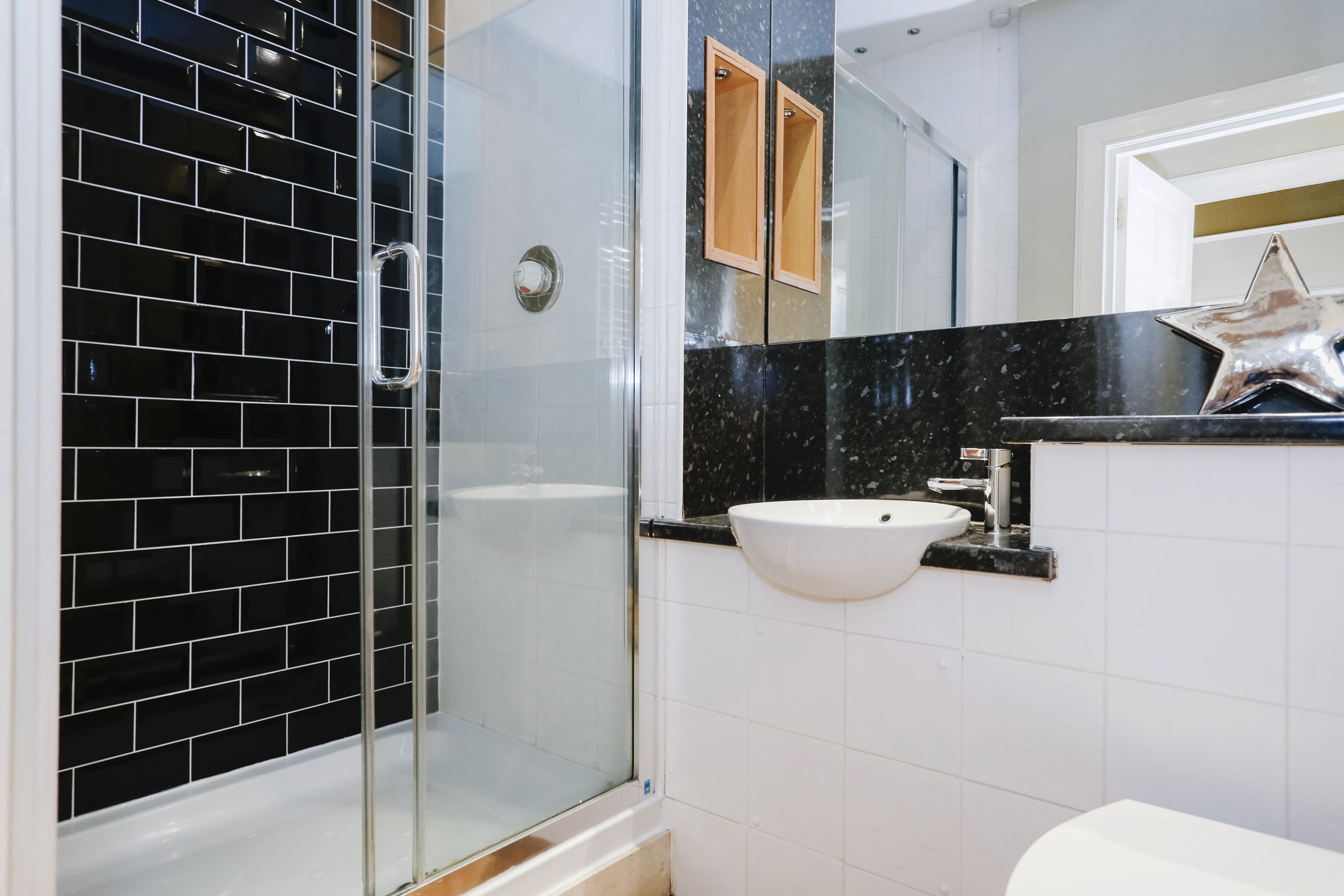 A bathroom with a glass-enclosed shower, a white sink, and a mirror with a star decoration.