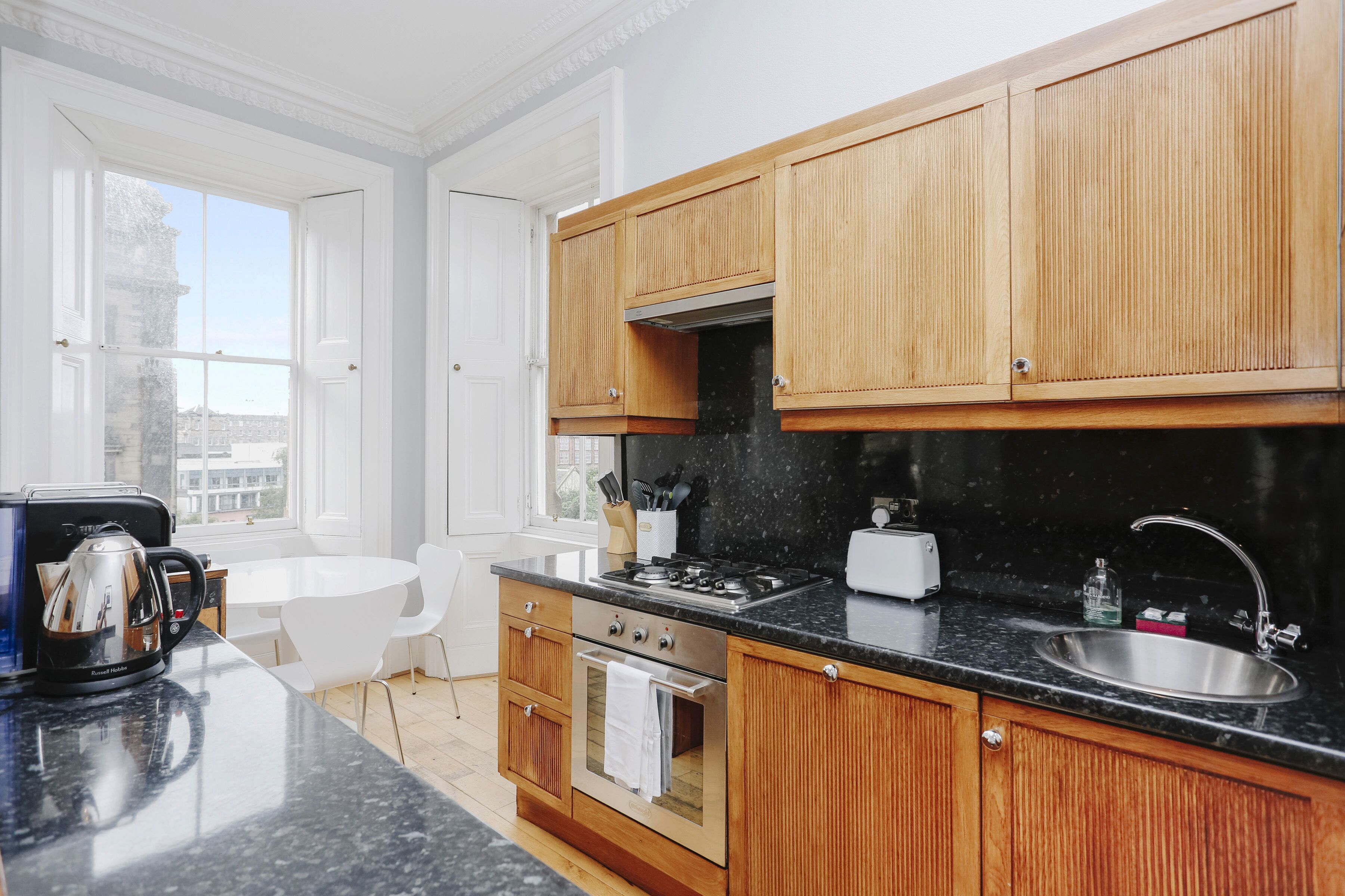 Una cocina moderna con armarios de madera, una encimera negra, una estufa y un fregadero.