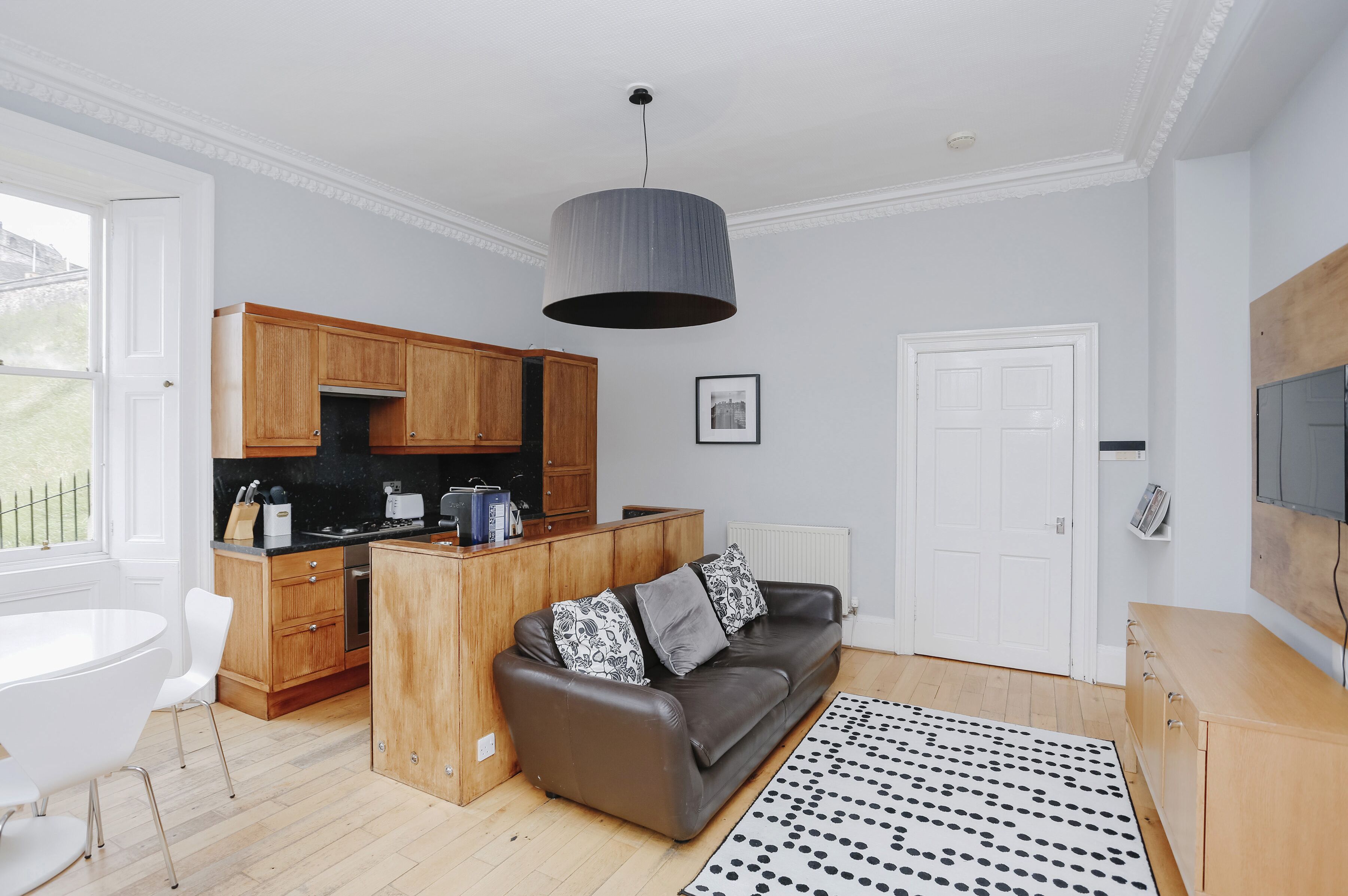 A modern kitchen with wooden cabinets, a black countertop, and a hanging light fixture.