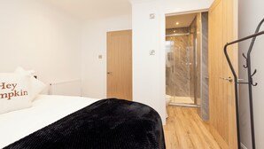 A hotel room with a bed, a black throw blanket, a wooden door, and a shower area. - JOIVY 3BR Flat in Haymarket with Free Parking (Edinburgh)