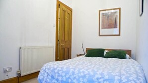 Ein Schlafzimmer mit einem Bett, einem Heizkörper, einer Holztür und einem gerahmten Bild an der Wand.