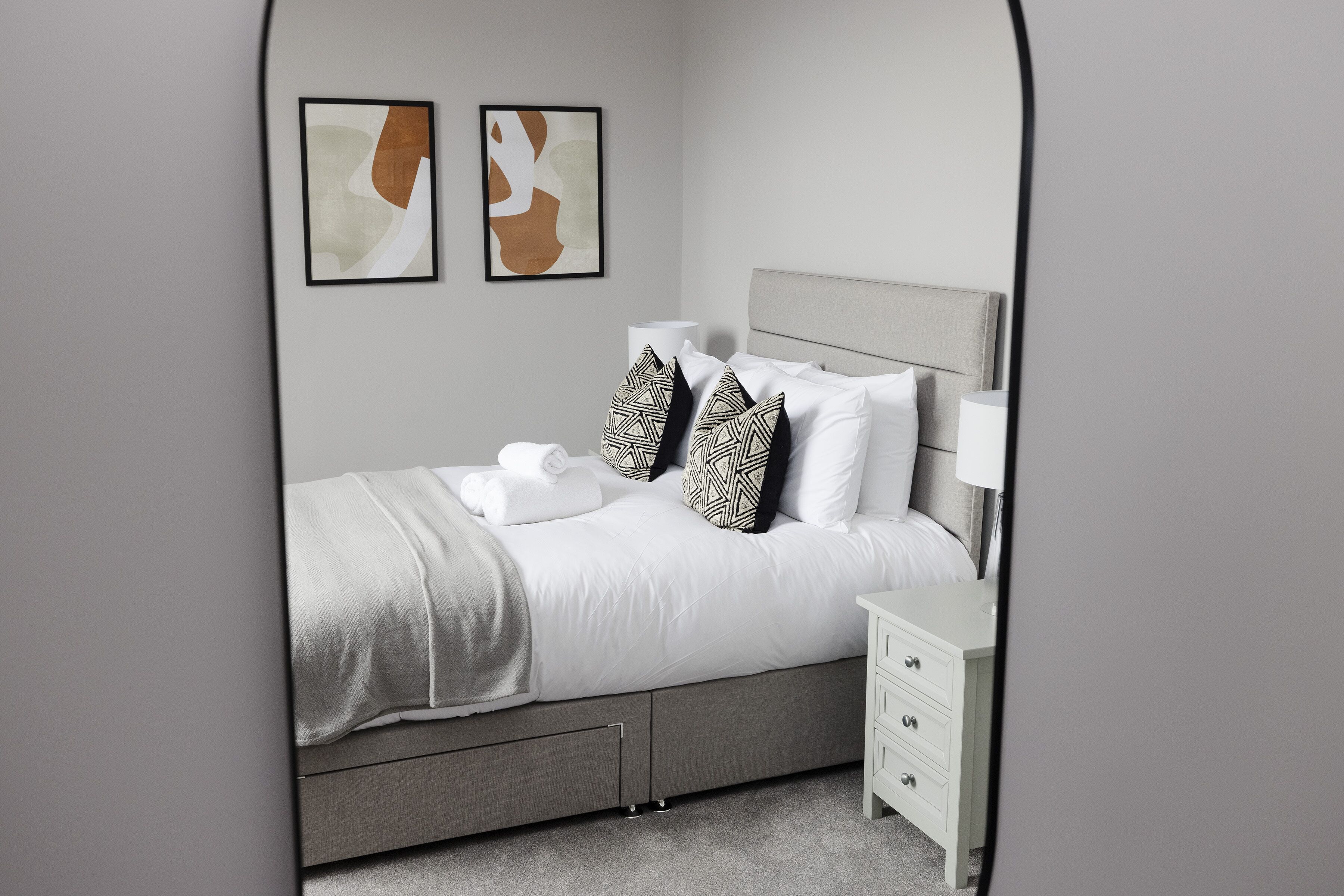 A neatly arranged bedroom with a bed, bedside tables, and a nightstand.