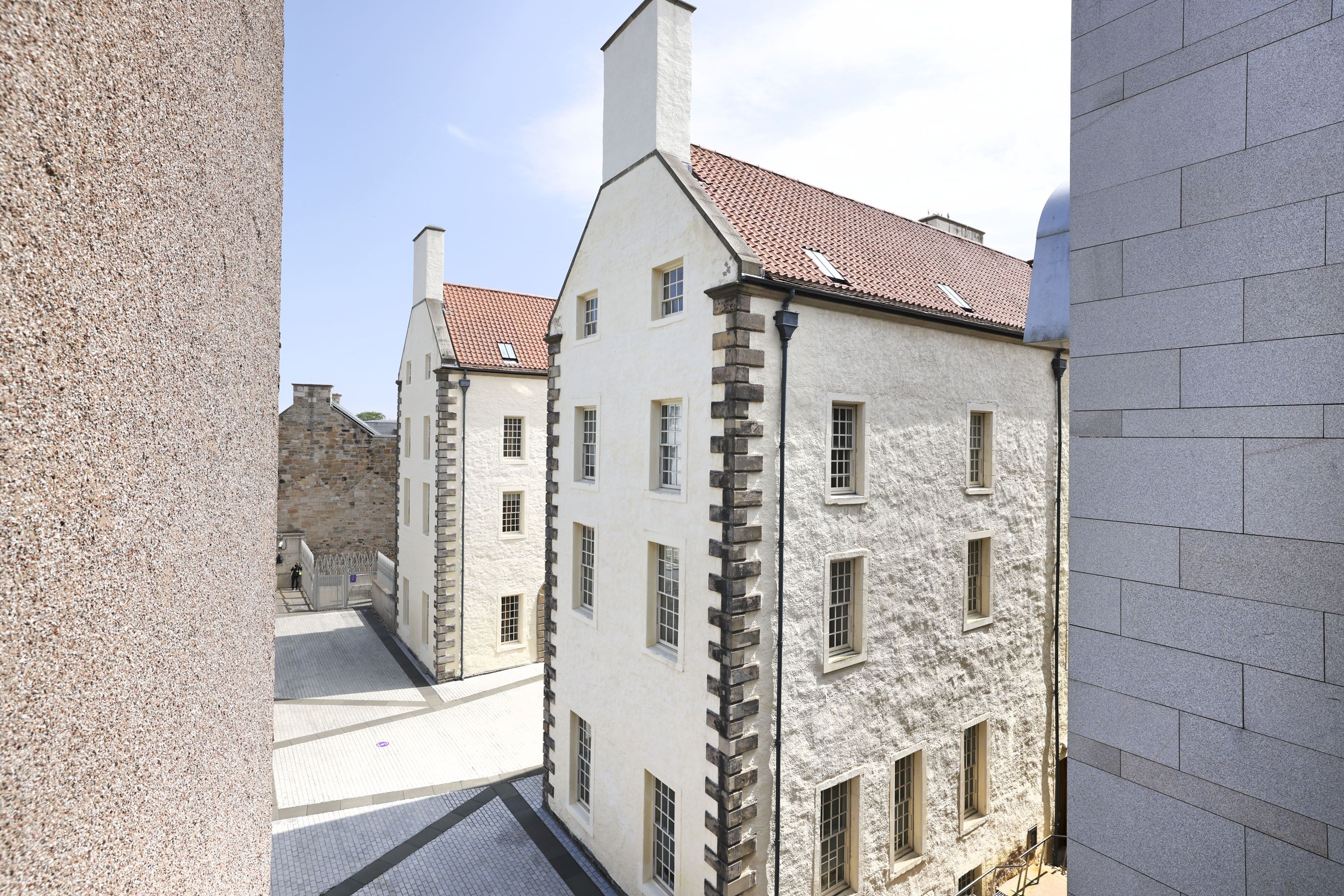 Une rue étroite bordée de bâtiments historiques aux façades en pierre et aux toits couverts de tuiles rouges.