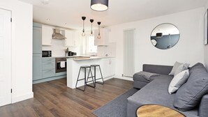 Une cuisine moderne avec des meubles blancs, un îlot central et des tabourets de bar.