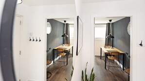 Un espace de salle à manger moderne avec une table et des chaises en bois, une suspension noire et un mur d’accent de couleur grise.