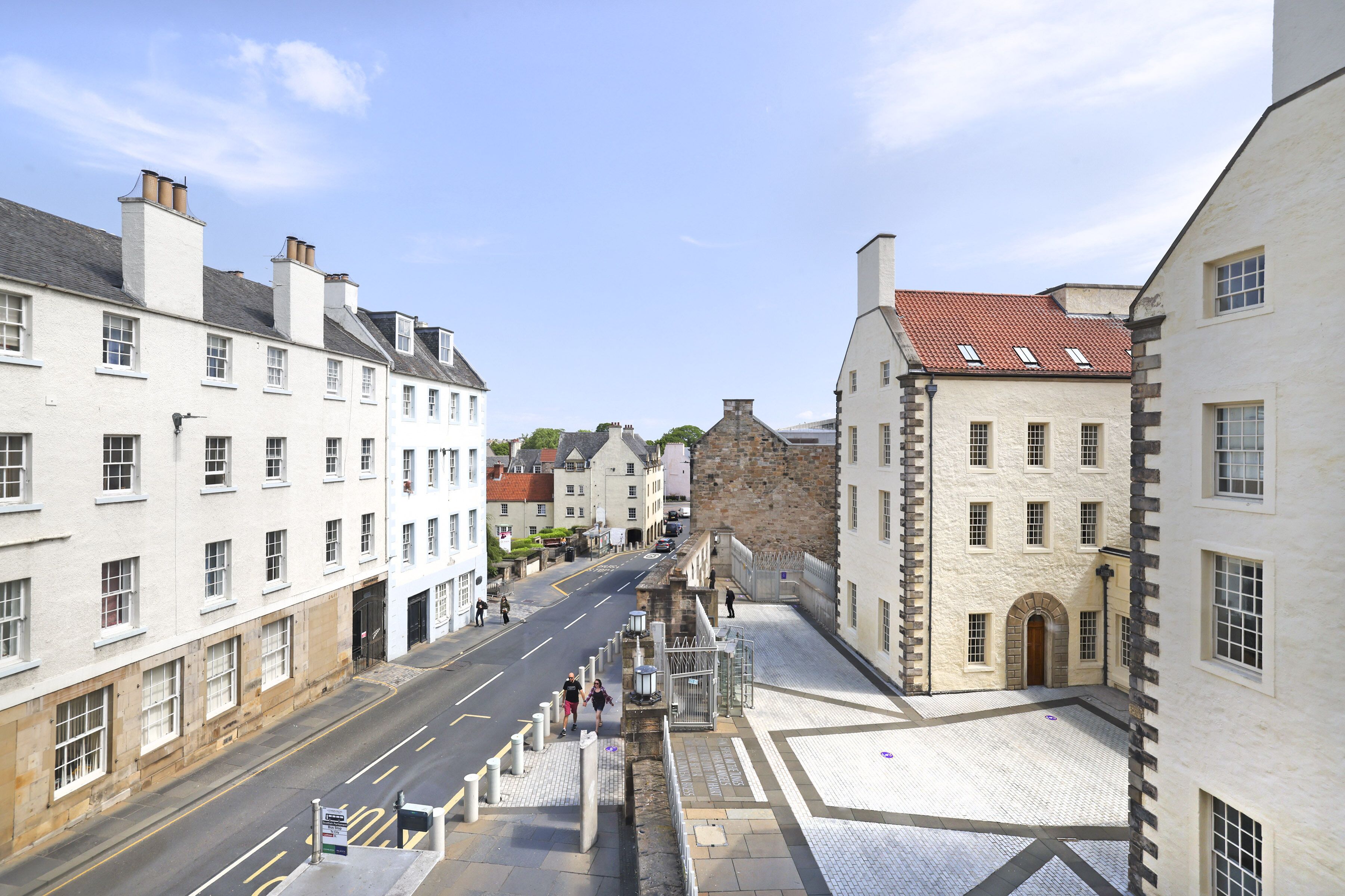 Straatbeeld met gebouwen aan beide zijden, een heldere lucht en een verhard gebied op de voorgrond.