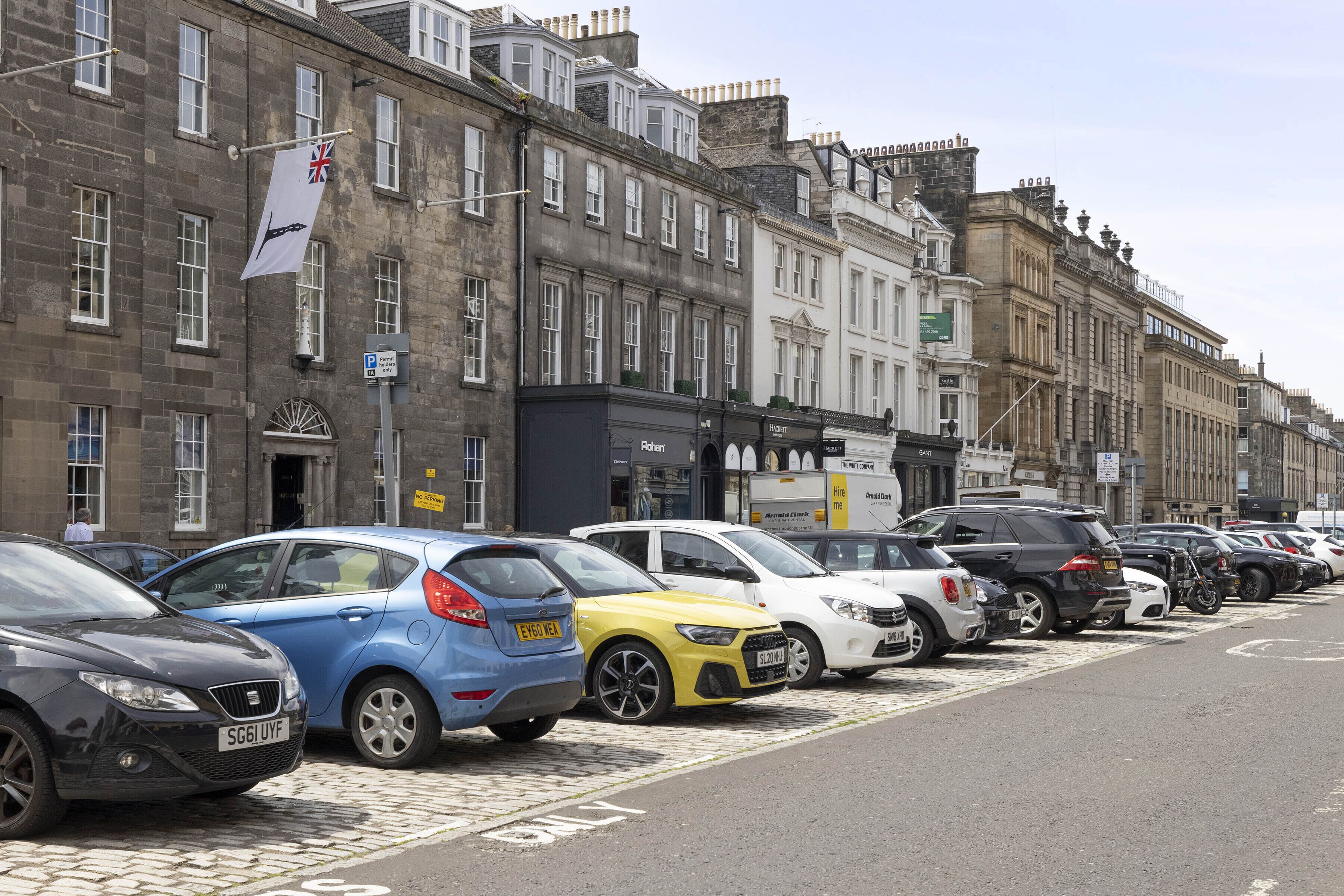 A row of parked cars along a street with historic buildings.