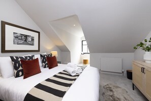 Ein modernes Schlafzimmer mit einem großen Bett, einem gerahmten Bild an der Wand, einem Heizkörper und einem Holzkabinett.