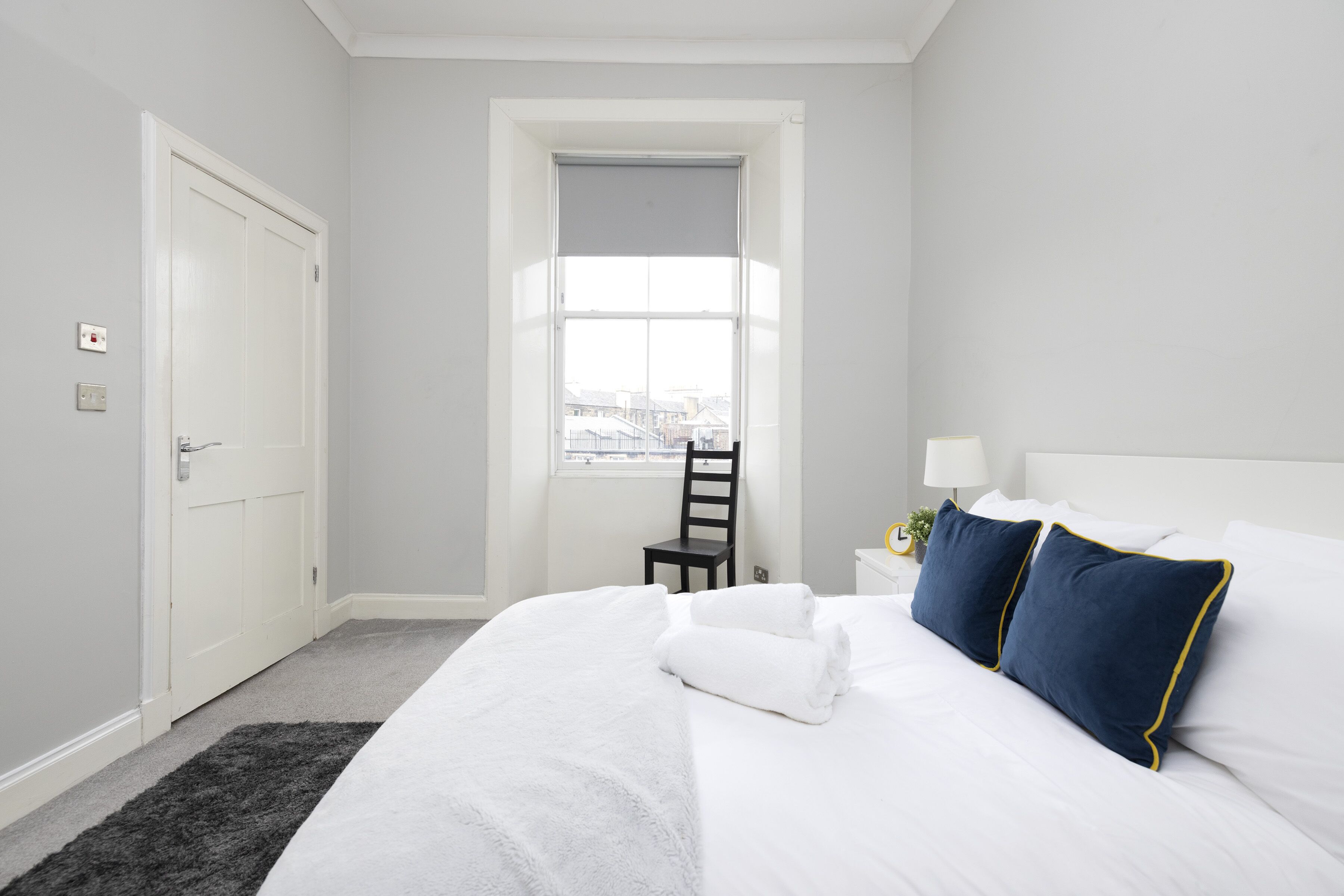 Une chambre d’hôtel avec un grand lit, une fenêtre donnant sur un beau paysage, une porte et une chaise.