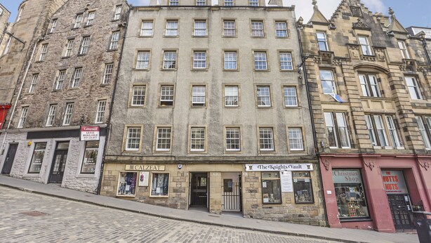 A historic building with multiple ground-floor shops, including a cafe and a Christmas shop. - JOIVY Heart Of Grassmarket 1 Br Apartment (Edinburgh)