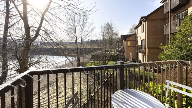 Ein Balkon mit Blick auf einen Fluss und Gebäude.