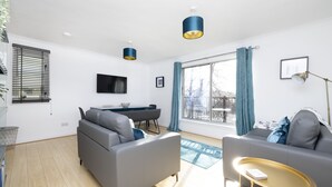 Ein modernes Wohnzimmer mit einem grauen Sofa, einem kleinen runden Tisch und einem Essbereich mit Tisch und Stühlen.