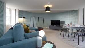 Un salon moderne comprenant un canapé, un téléviseur, une table à manger et des chaises.