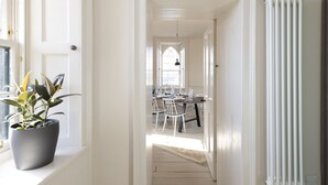 Un couloir menant à une salle à manger avec une table et des chaises, une plante en pot et un radiateur.