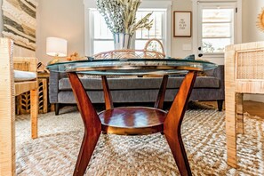 Un salon moderne avec une table basse en verre, des meubles en osier et un canapé gris.
