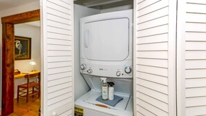 Une buanderie équipée d’un lave-linge, d’un sèche-linge et d’une bouteille de lessive.