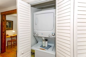 A laundry room with a washing machine, a dryer, and a detergent bottle.