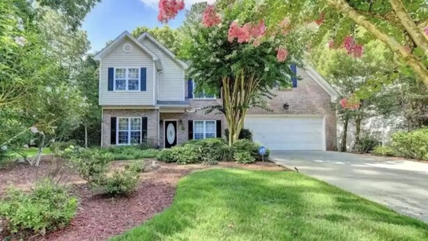 A two-story house with a front porch, a garage, and a well-maintained lawn. - Spacious, Relaxed 5 Bedroom Getaway (LILBURN)