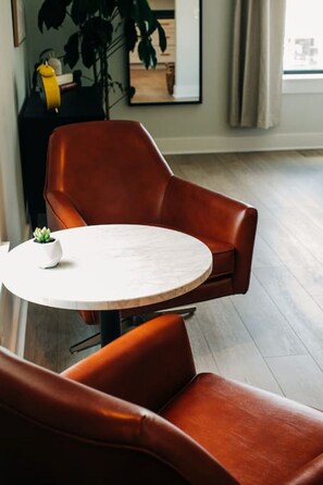 A modern living room with a round marble table and two brown leather armchairs. - Market #10 · Stellar Suites | Queen of Nulu | Boutique Hotel (Louisville)
