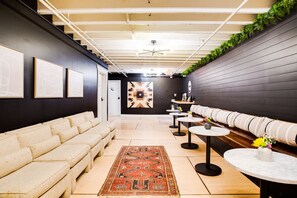 Ein stilvoller Lounge-Bereich mit einer Couch, Tischen und Kunstwerken an den Wänden.