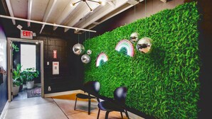 A modern interior with a green wall, two black chairs, and a ceiling light fixture.