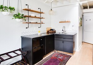 Cocina moderna con gabinetes negros, encimera blanca y plantas colgantes.
