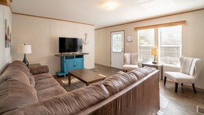 A living room with a brown sofa, a television on a blue cabinet, a coffee table, and a chair.