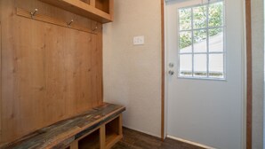 A wooden bench, a door with a window, and a wall-mounted coat rack.