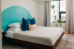 A bed with a teal headboard, white and blue pillows, and a beige blanket. - Market #1 · Stellar Suites | King Loft | NuLu | Boutique Hotel (Louisville)