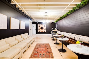 Ein stilvoller Lounge-Bereich mit einer Couch, Tischen und Kunstwerken an den Wänden.