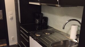 Eine kleine Küche mit Herd, Spüle und Kaffeemaschine.