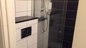 Ein kleines Badezimmer mit Toilette, Dusche und einer Ablagefläche.