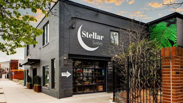 Un edificio con un cartel que dice "Stellar Suites" y un escaparate visible con puertas de cristal.
