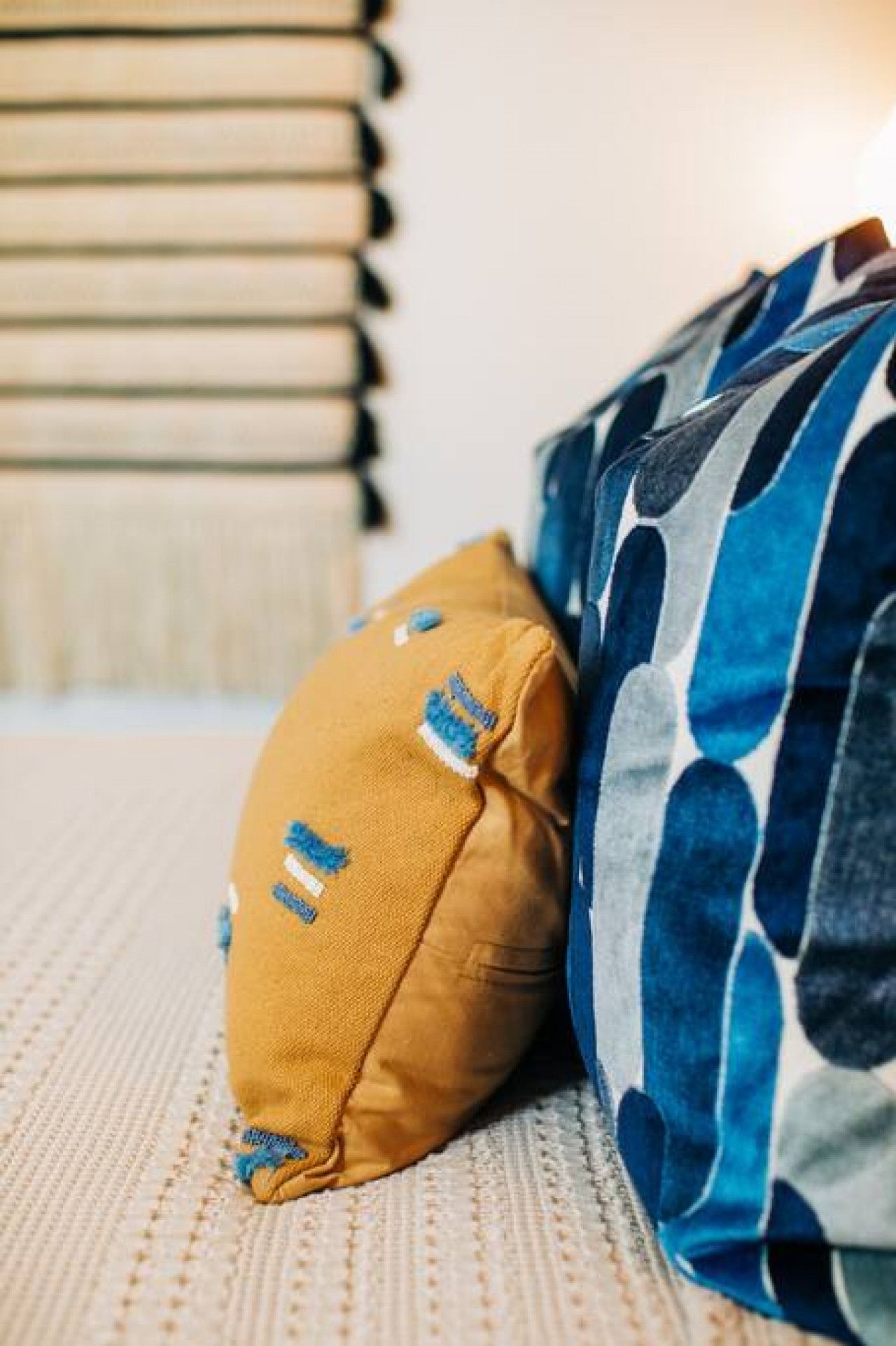 A bed with a patterned pillow and a plain pillow.