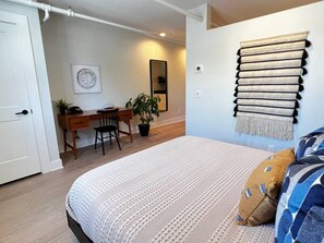 Ein Schlafzimmer mit Bett, Schreibtisch, Stuhl und einer Topfpflanze.