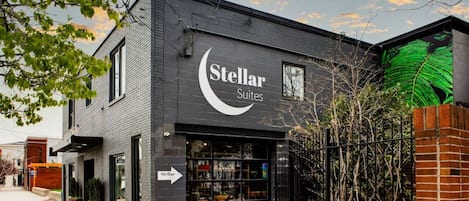 A building with a sign reading "Stellar Suites" and a visible storefront with glass doors.