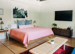 Ein Schlafzimmer mit Bett, Nachttisch, Lampe und einem Bild an der Wand.