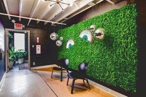 Un intérieur moderne avec un mur vert, deux chaises noires et un luminaire suspendu au plafond.
