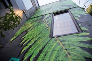 A building with a green leaf pattern on the exterior wall and a window. - Market #8 · Stellar Suites | The  Sunset Suite | NuLu | Bikes (Louisville)