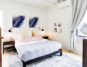 Ein Schlafzimmer mit einem Bett, zwei Nachttischen, einem Fenster mit Vorhängen und Wandbildern.
