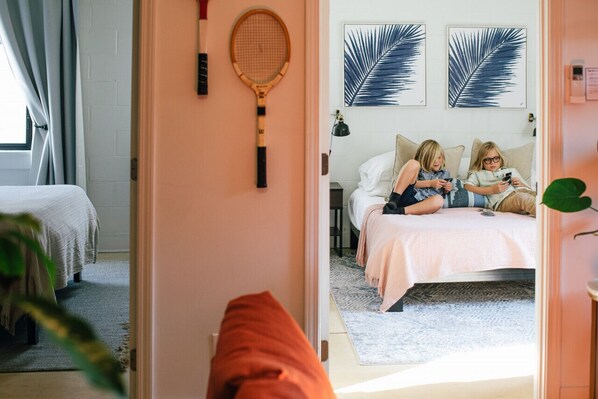Une chambre à coucher avec un lit, une raquette de tennis et deux œuvres d’art représentant des feuilles, encadrées et accrochées au mur.