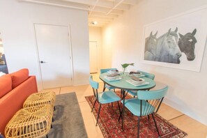 A dining area with a round table, blue chairs, and a rug. - Market #8 · Stellar Suites | The  Sunset Suite | NuLu | Bikes (Louisville)