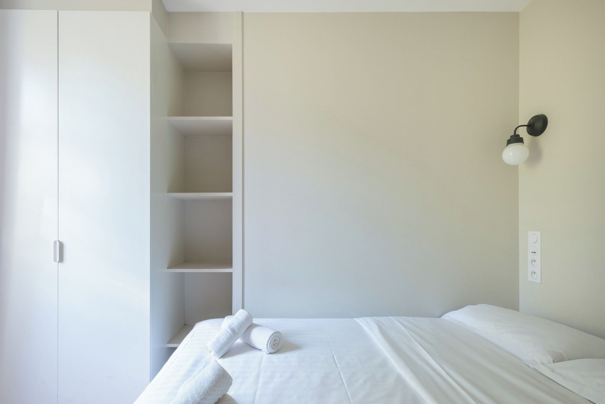 Ein Schlafzimmer mit einem Bett, einem Kleiderschrank und einer Wandleuchte.